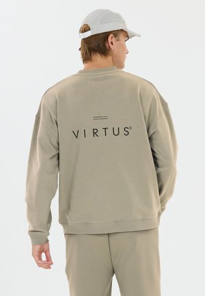 Homme portant un sweat-shirt beige et un pantalon avec le texte « VIRTUS » dans le dos, portant également une casquette perforée gris clair, de dos.