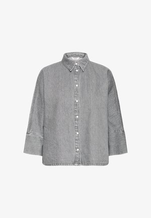 Chemise en denim gris avec un col classique, une fermeture à boutons sur le devant, des épaules tombantes et des manches longues. Elle présente une finition texturée et des coutures latérales.
