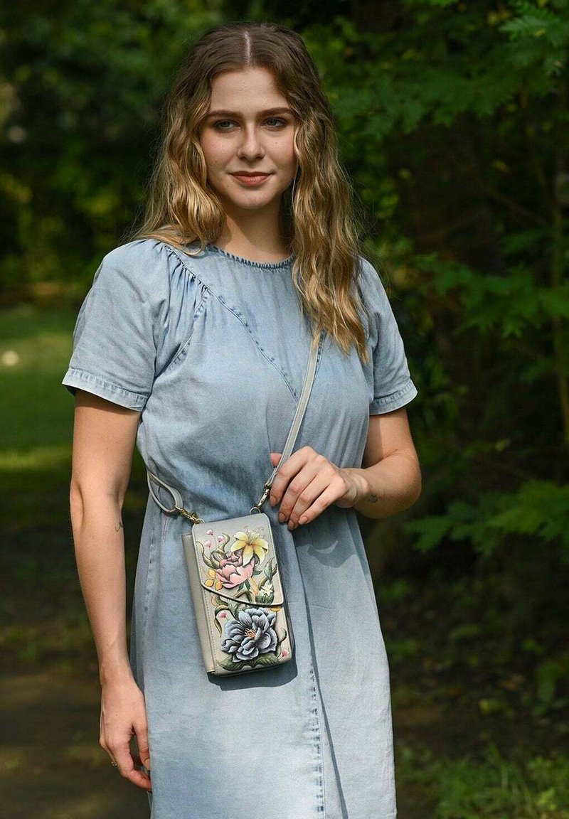 Lichtdenim jurk met korte mouwen, met een gerimpeld ontwerp, gecombineerd met een grijze schoudertas versierd met bloempatronen in roze en blauw.