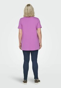 T-shirt viola a maniche corte con taglio dritto, di colore uniforme e orlo arrotondato, abbinata a jeans skinny blu scuro e scarpe casual.