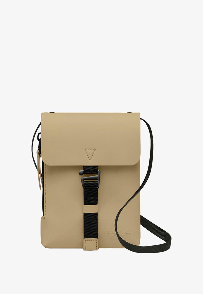 Bolso cruzado de cuero vegano beige con cierre de solapa, correa de nylon negra y detalle de hebilla ajustable. Diseño minimalista con logo en relieve.