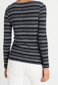 Chemise à manches longues de couleur navy avec des rayures horizontales blanches, au design ajusté et avec un col rond. Le tissu semble doux avec un léger extensibilité.