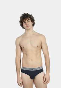 Slip in cotone elasticizzato blu navy con cinturino elastico grigio con il logo "EMPORIO ARMANI"; design aderente con texture liscia.