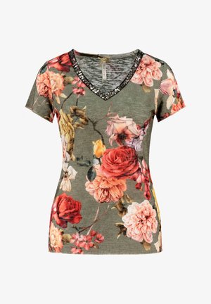 V-kauluksellinen kukkakuviollinen t-paita oliivinvihreästä kankaasta, jossa on suuria vaaleanpunaisia, punaisia ja keltaisia kukkia, mustilla paljeteilla koristeltu kaula-aukko.