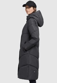 Long puffer coat in dark gray, featuring a hood, side pockets, and a quilted design. The material appears smooth and insulated.