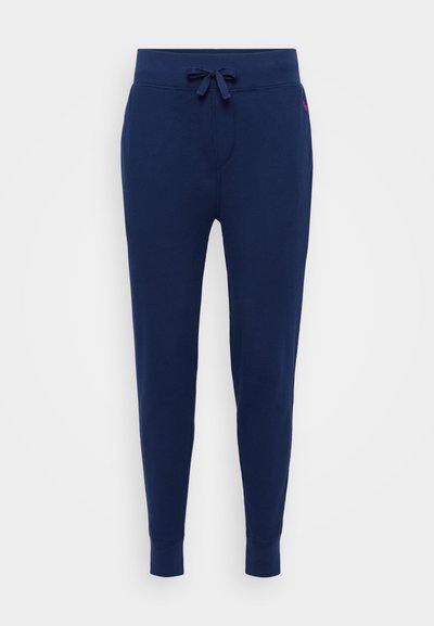 Pantalons de jogging bleu marine en texture côtelée avec taille élastique à cordon de serrage et poignets aux chevilles. Comprend des poches latérales et un détail de marque minimal.
