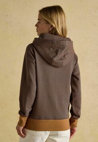 Pruun ja tumesinine triibuline kapuutsiga sviiter ribadega cuffs ja ääres. Pehme kangas mugava lõikega, vaadates tagant.