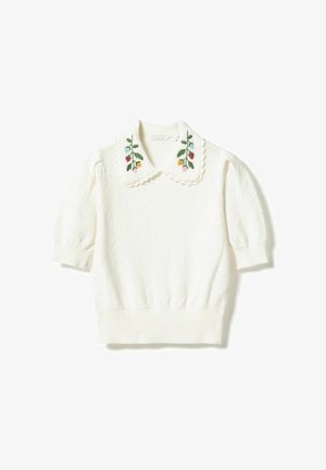 Valge lühikeste varrukatega kampsun, millel on tekstureeritud teemantmuster ja laineline krae, mille kummalgi küljel on värvikas lillepits.