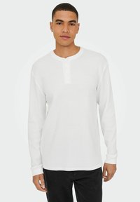 Weißes Langarm-Henley-Shirt mit strukturiertem Strickmuster, runder Ausschnitt und einer Knopfleiste mit drei Knöpfen. Einfaches Design, lässige Passform.