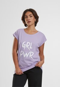 Lilla kortærmet t-shirt med rund halsudskæring og fed hvid "GRL PWR" lettering. Blødt bomuldsstof, afslappet pasform og opsmøgede ærmer.