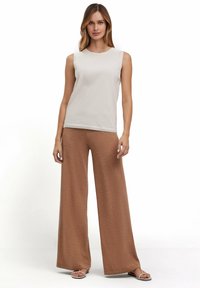 Lichtbeige mouwloze top met een ronde halslijn, gecombineerd met brown wijde broek. Glad stoffen textuur zonder zichtbare patronen of accenten.