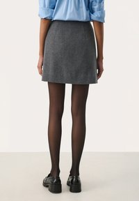 Grå uld mini nederdel parret med sorte gennemsigtige strømpebukser og sorte læder loafers, med et enkelt design og en lige silhuet.