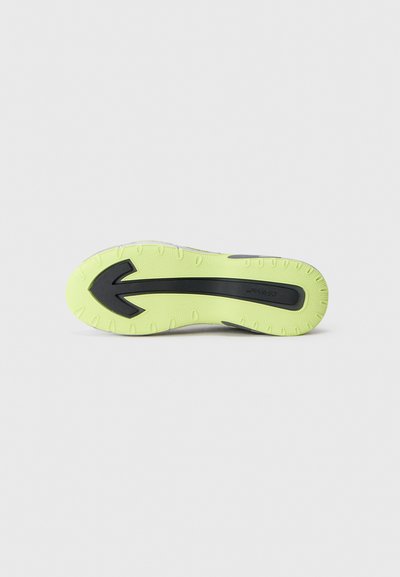 Sneakeru zole ar spilgtu dzeltenu gumijas pamatni, melniem akcentiem un strukturētām berzes rakstiem, kas izstrādāta, lai nodrošinātu saķeri un izturību.