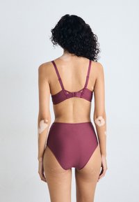 Burgundy bikini set featuring a bralette with adjustable straps and high-waisted bottoms. Smooth fabric with minimal hardware and clean lines.
