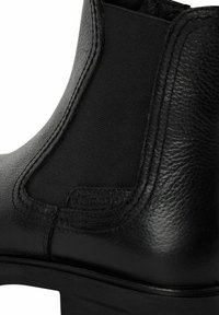 Černé kožené kotníkové boty s elastickými bočními panely, texturovaným povrchem a robustním podpatkem. Logo viditelné na boku.