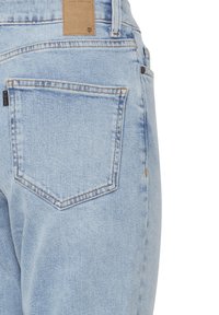 Jeans de mezclilla azul claro con un bolsillo trasero único de forma rectangular y costuras visibles. La tela tiene una textura clásica tejida.
