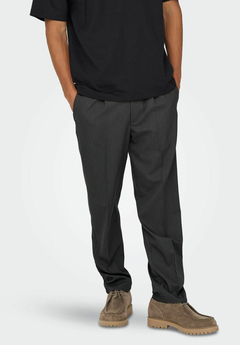 Gray tailored trousers made from lightweight fabric, featuring a straight-leg design and front pleats, paired with tan suede shoes.