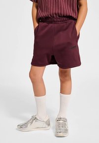 Vinröda shorts med elastisk midja och sidofickor. Kombinerade med vita strumpor och silverfärgade sneakers med enkel design.