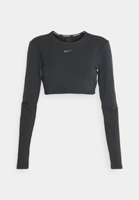 Czarny krótki top z długim rękawem wykonany z gładkiego materiału, z okrągłym dekoltem z napisem "Nike Pro" i małym srebrnym logo Nike na piersi.