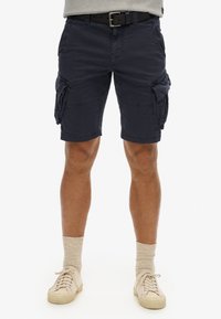 Marine cargo shorts med en afslappet pasform, lavet af letvægtsstof, med flere sidelommer og opfoldede kanter. Sammen med beige sneakers.