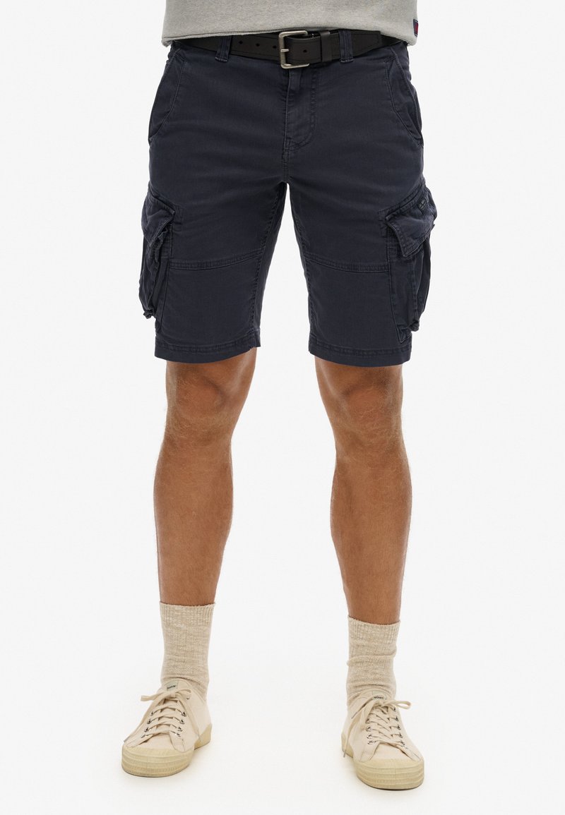 Marine cargo shorts med en afslappet pasform, lavet af letvægtsstof, med flere sidelommer og opfoldede kanter. Sammen med beige sneakers.