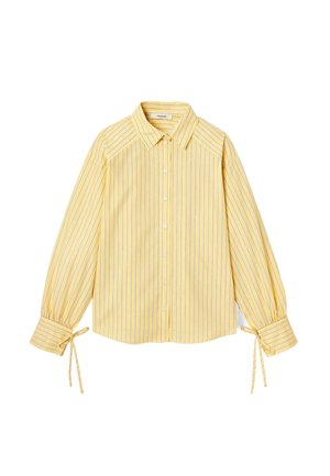 Blouse rayée jaune avec un col, fermeture à boutons sur le devant, et manches longues avec des liens ajustables aux poignets. Tissu doux et léger.