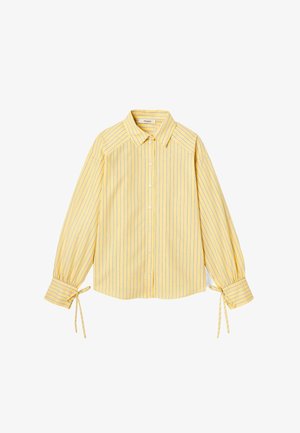 Blouse rayée jaune avec un col, fermeture à boutons sur le devant, et manches longues avec des liens ajustables aux poignets. Tissu doux et léger.