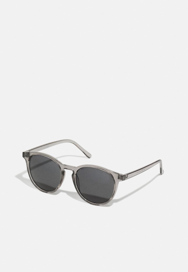Occhiali da sole rotondi con montatura grigia trasparente, lenti scure e aste sottili. Caratterizzati da un design minimalista senza motivi o decorazioni visibili.