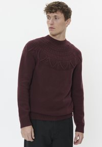 Maglione lavorato a maglia bordeaux con un colletto a girocollo, maniche a coste e un yoke testurizzato e decorato, progettato per una silhouette aderente.