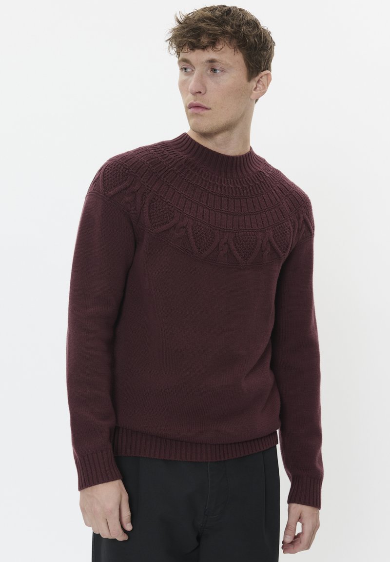 Maglione lavorato a maglia bordeaux con un colletto a girocollo, maniche a coste e un yoke testurizzato e decorato, progettato per una silhouette aderente.