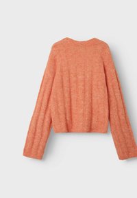 Pomarańczowy sweter robiony na drutach o skróconym kroju, z szerokimi rękawami i miękką strukturą. Tył ma okrągły dekolt i subtelne prążkowanie.