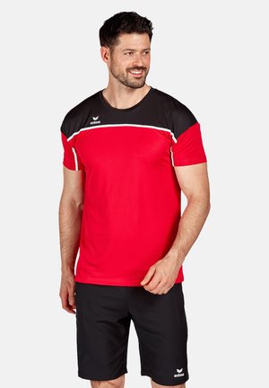 Camiseta deportiva roja con hombros negros y acentos blancos; mangas cortas, escote redondo. Combinada con pantalones cortos negros que presentan un logo.