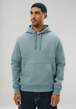 Helle blauen Hoodie aus weichem Stoff, mit einer Fronttasche, Kapuze mit Kordelzug und gerippten Bündchen. Kombiniert mit dunklen Jeans.