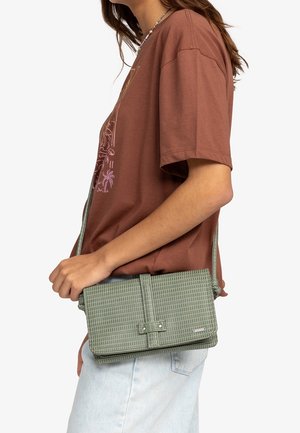 Grön vävd axelväska med en strukturerad yta, med ett tryckknappslås och en framflik. Remmen är justerbar.