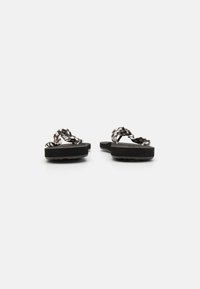 Black and white checkered flip-flops with woven straps, featuring a thick black sole and textured footbed.