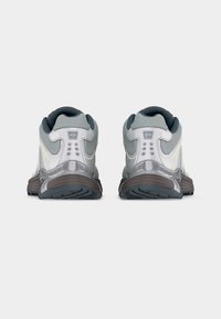 Par športnih sivičev prikazanih od zadaj z oblazinjenimi ovratniki in vzorčastimi gumijastimi podplati na enostavni podlagi.