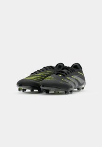 Black soccer cleats with neon green accents, textured synthetic upper, and transparent molded studs for grip on grass surfaces.