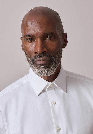 White button-up shirt with a pointed collar, smooth texture, and subtle sheen, worn by a man with a short beard and gray facial hair.