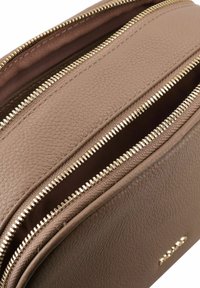 Bolso de cuero marrón con dos compartimentos con cremallera y herrajes en tono dorado. Superficie texturizada, forma rectangular, diseño minimalista.