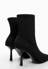 Bottines à talons hauts noires en tissu lisse, avec un design ajusté, un bout pointu et un talon aiguille fin.