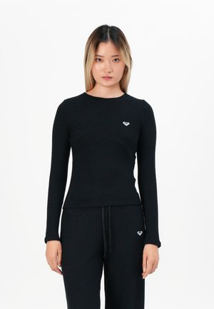 Black ribbed long-sleeve top with a round neckline and a small white heart logo on the chest. Material appears soft and textured.