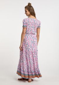 Rochie maxi de culoare roz pal, cu un imprimeu floral, mâneci scurte tip bufant, spate plisat și un tiv cu model ce conține accente de portocaliu și albastru.