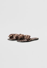 Sandály s leopardím potiskem, širokou mašlí, plochou podrážkou, černým základem a jemnou texturou, které nabízejí pohodlný design vhodný pro teplé počasí.