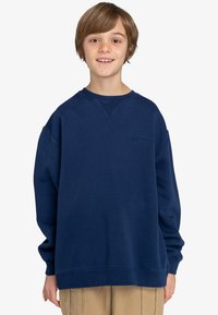 Felpa blu navy con scollatura tonda e polsini a coste. Presenta un logo discreto sul petto e una vestibilità morbida e comoda.