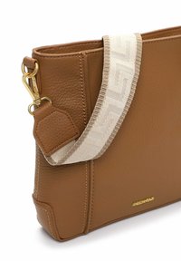 Borsa a tracolla in pelle marrone con superficie testurizzata, caratterizzata da una tracolla decorativa crema e dettagli in metallo dorato.