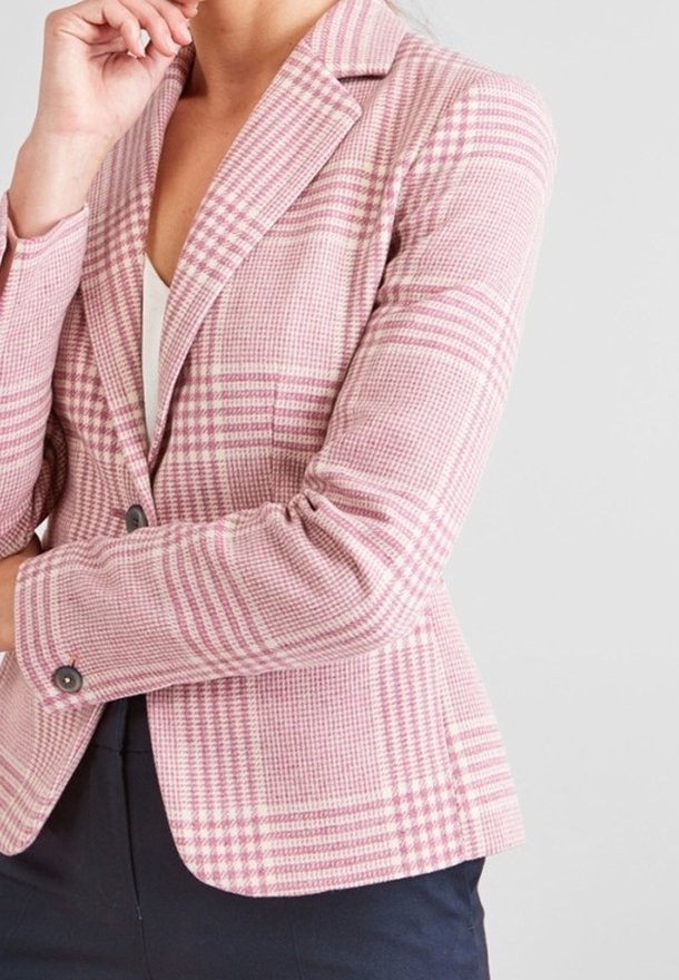 Blazer à carreaux rose et crème avec revers notés, deux boutons et coupe ajustée. Présente des épaules structurées et une légère texture dans le tissu.