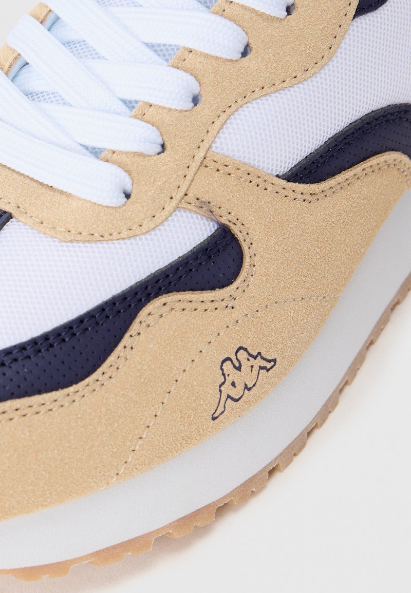 Beige, weiße und marineblaue Sneaker aus Wildleder und Mesh. Mit strukturierten Überzügen, weißen Schnürsenkeln und einem Logo-Akzent nahe der Sohle.