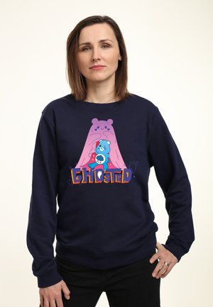 Marine sweatshirt med et tegneserie-design af en blå bjørn og et pink spøgelse. Tekst "GHOSTED" i orange og lilla, blødt stof, afslappet pasform.