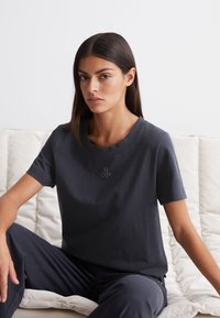 Mörkgrå t-shirt med kort ärm, tillverkad av mjukt material, med rund halsringning och en subtil "MOP"-logga på bröstet.