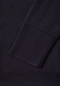 Pull en tricot bleu marine foncé avec des poignets et un ourlet côtelés pour une finition texturée. Tissu doux au toucher lisse.